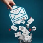 A top-down view of a clean, minimalist desk with a laptop open to a nearly empty email inbox, next to a cup of coffee and a small plant.