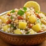 A close-up shot of fluffy, non-sticky Sabudana Khichdi in a white bowl, showing individual tapioca pearls, garnished with roasted peanuts and cilantro.