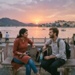 एक ट्रैवलर और स्थानीय व्यक्ति चाय पीते हुए और एक-दूसरे के साथ मुस्कुराते हुए। (A traveler and local person drinking tea and smiling together.)